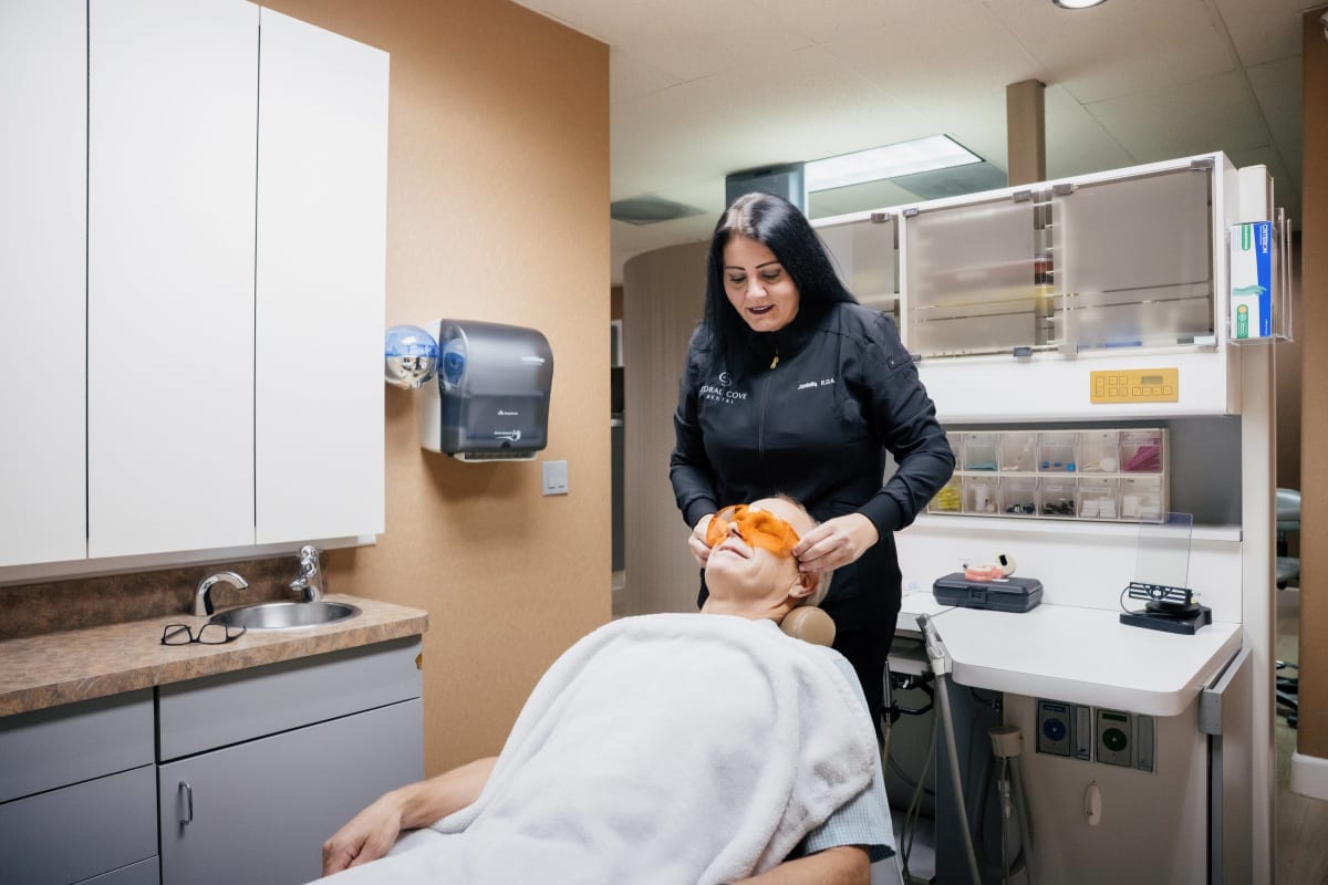 Dental professional examining a patient in a clinical treatment room at Coral Cove Dental