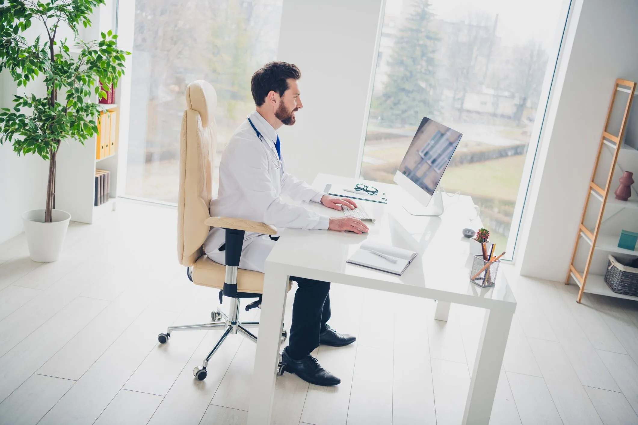 Doctor working at a desktop computer in a bright medical office