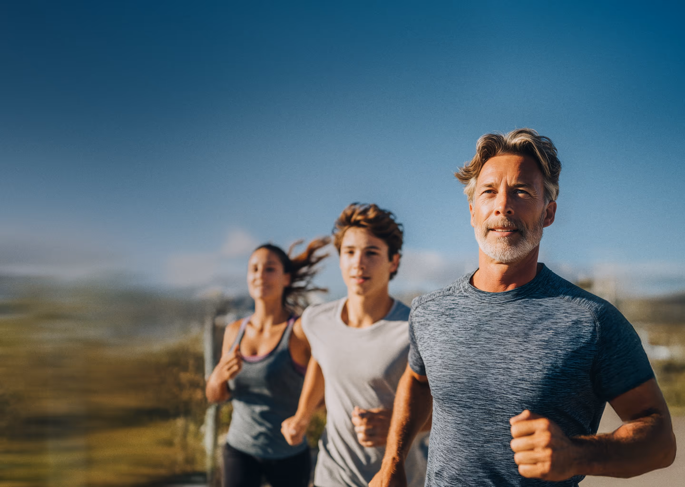 Man, young man, and a woman running outside
