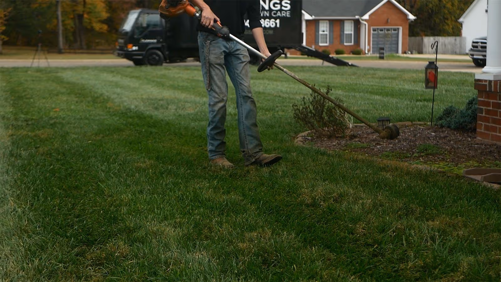 Crew member using weed whacker for detailed lawn edging and trimming in Dickson County Tennessee