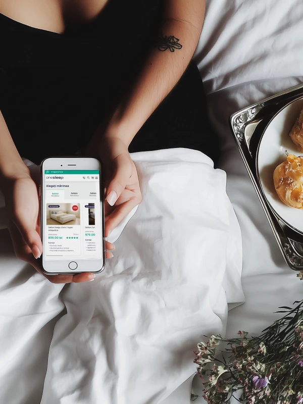 A woman holding an iphone with the onesleep.com e-commerce website open