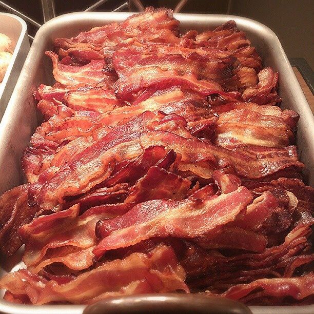 Tray filled with several crispy cooked bacon strips stacked together.