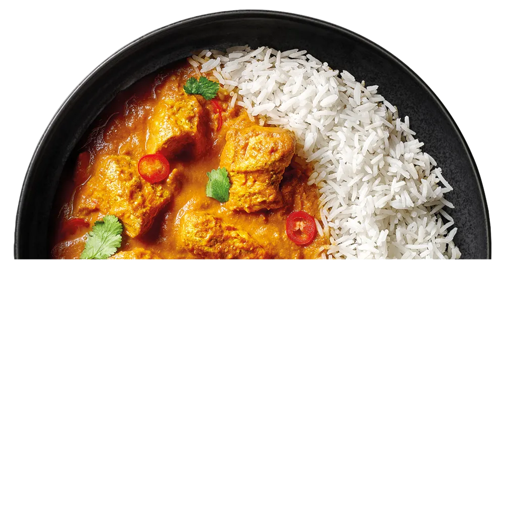 Miska s rýží a pikantním kuřecím kari vindaloo zdobeným koriandrem a červenou chilli papričkou.