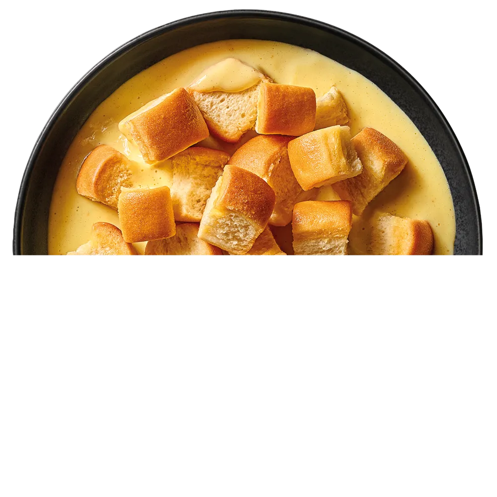 Černý talíř s kousky světlých buchet ve vanilkovém pudinku.