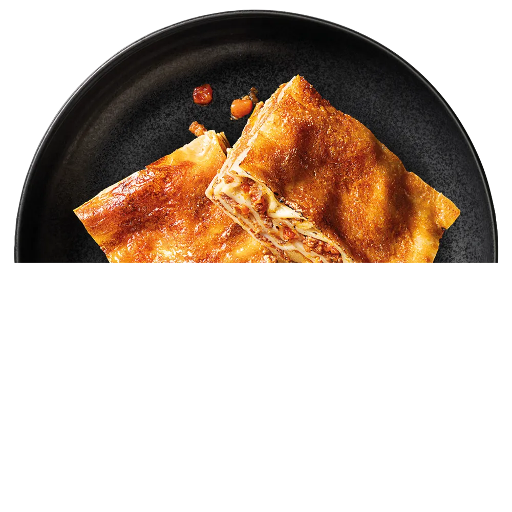 Dva porce zlatavé zapečené lasagne na černém talíři.