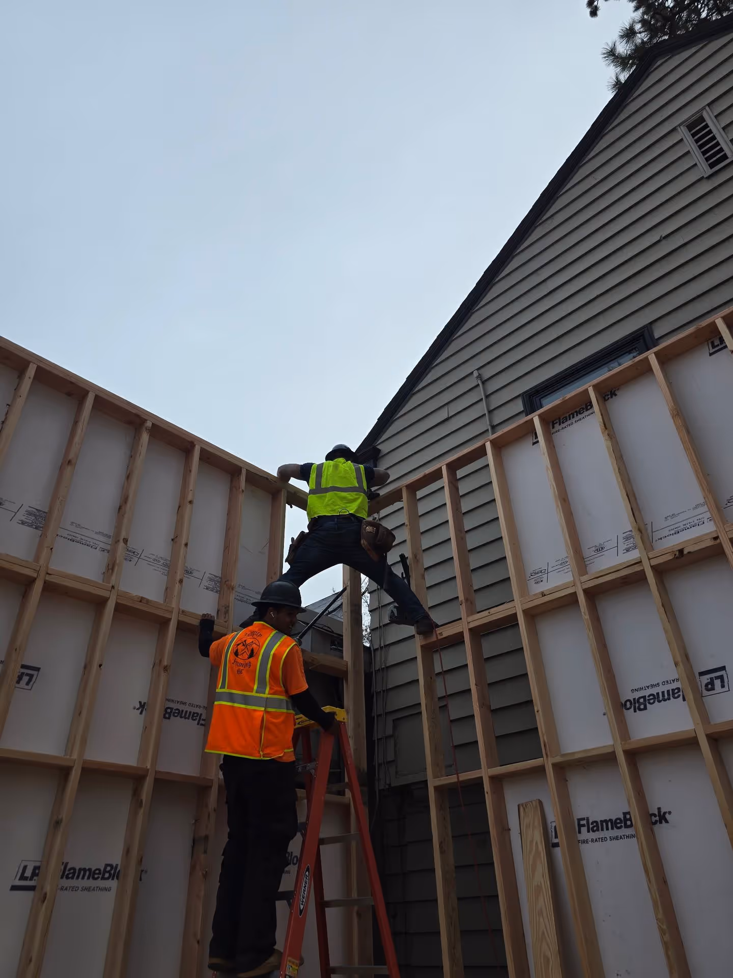 A man standing on a ladder working on a house.
