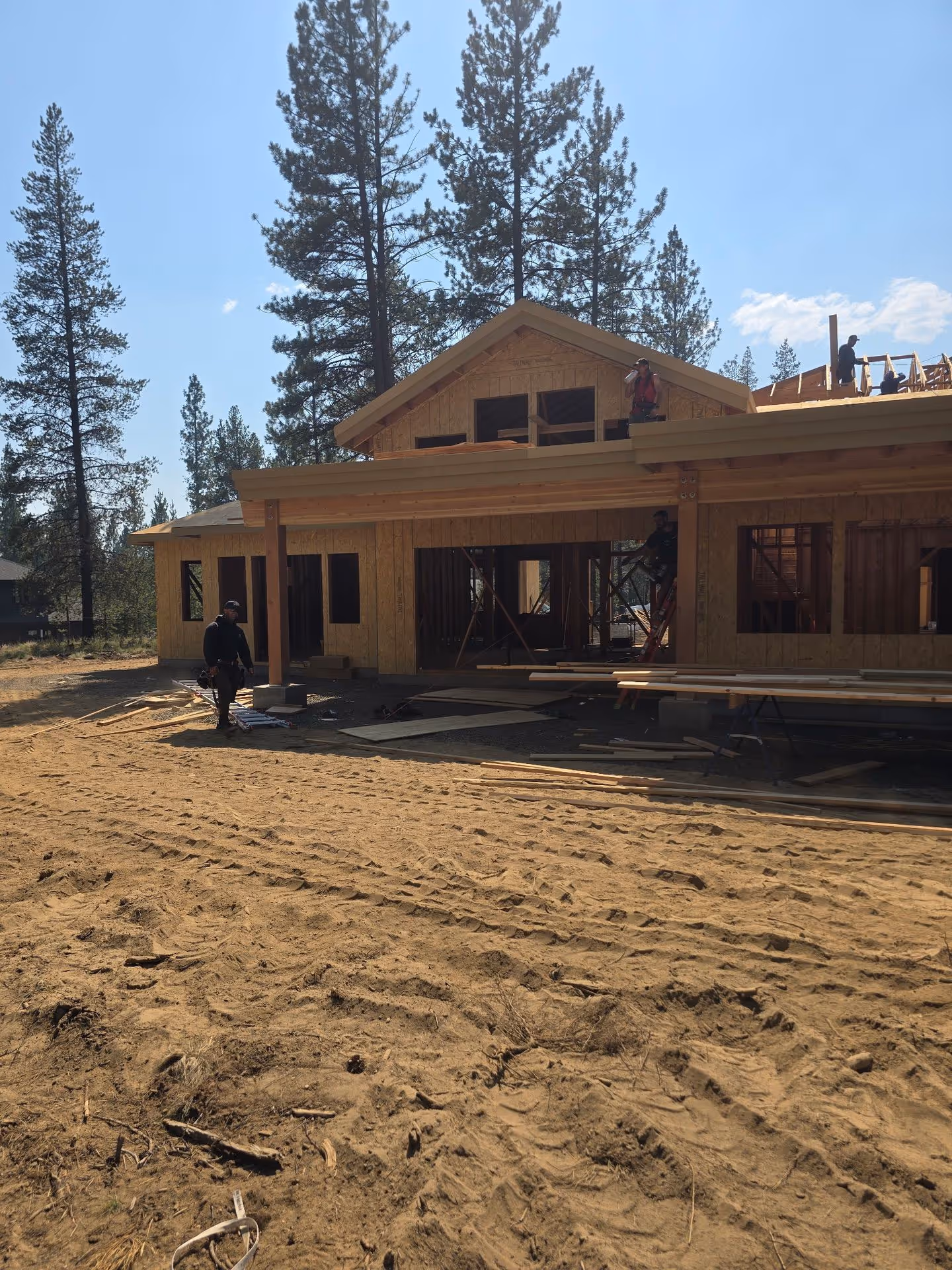 A house being built in the middle of a dirt field.