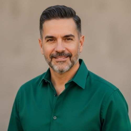 Man in green shirt smiling against a neutral background