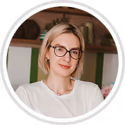 Smiling woman with short blonde hair and glasses wearing a white top.