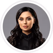 Portrait of a woman with long dark hair wearing a black top against a gray background.