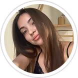 Young woman with long brown hair wearing a black top, smiling softly in a close-up selfie.