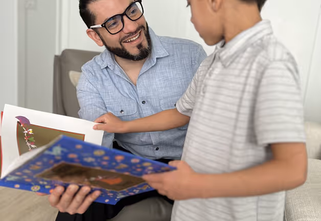 Man reads to boy in San Jose, illustrating all-ages psychotherapy focus on long-term health and child therapy.