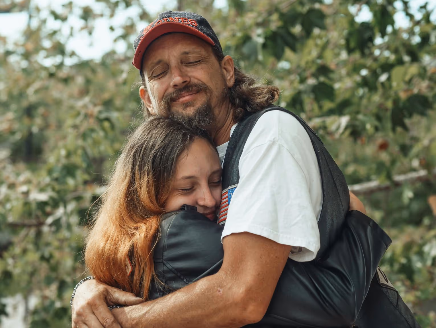 Father hugging daughter warmly after substance use recovery program.