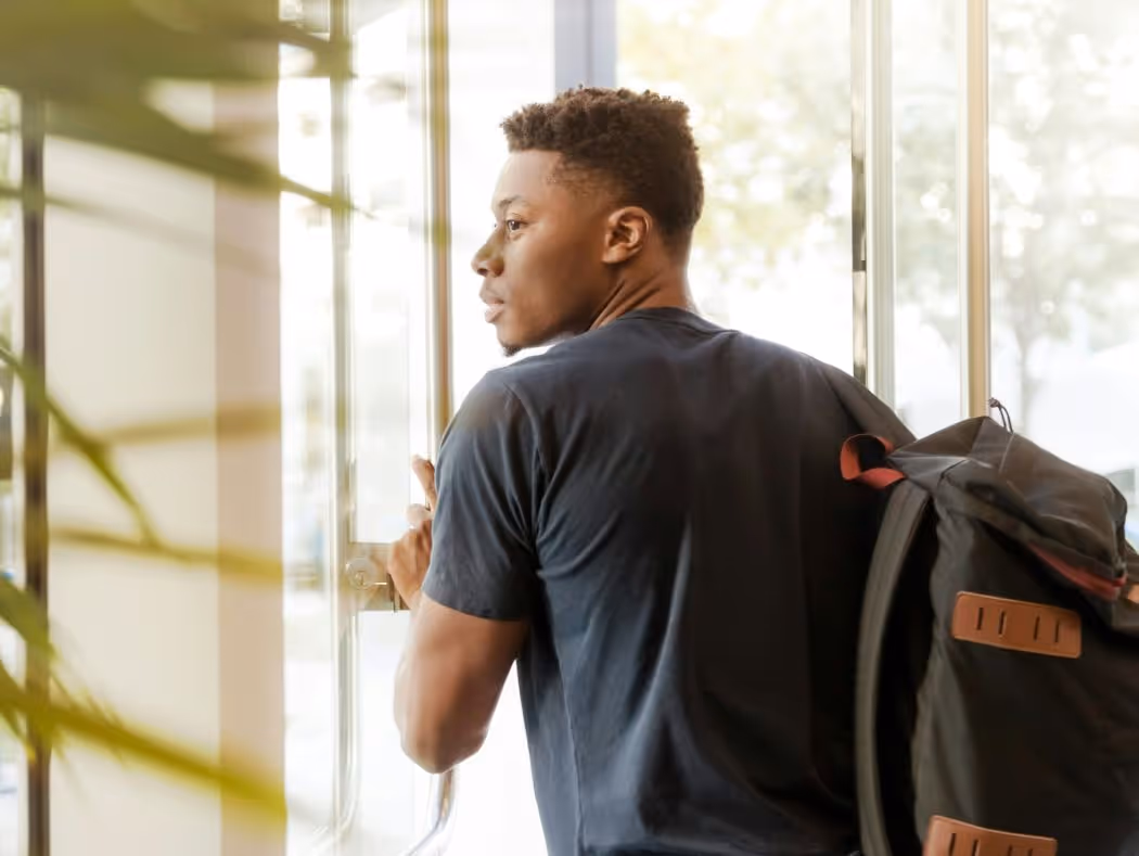 Young college man with a backpack leaving mental health session, navigating stress.