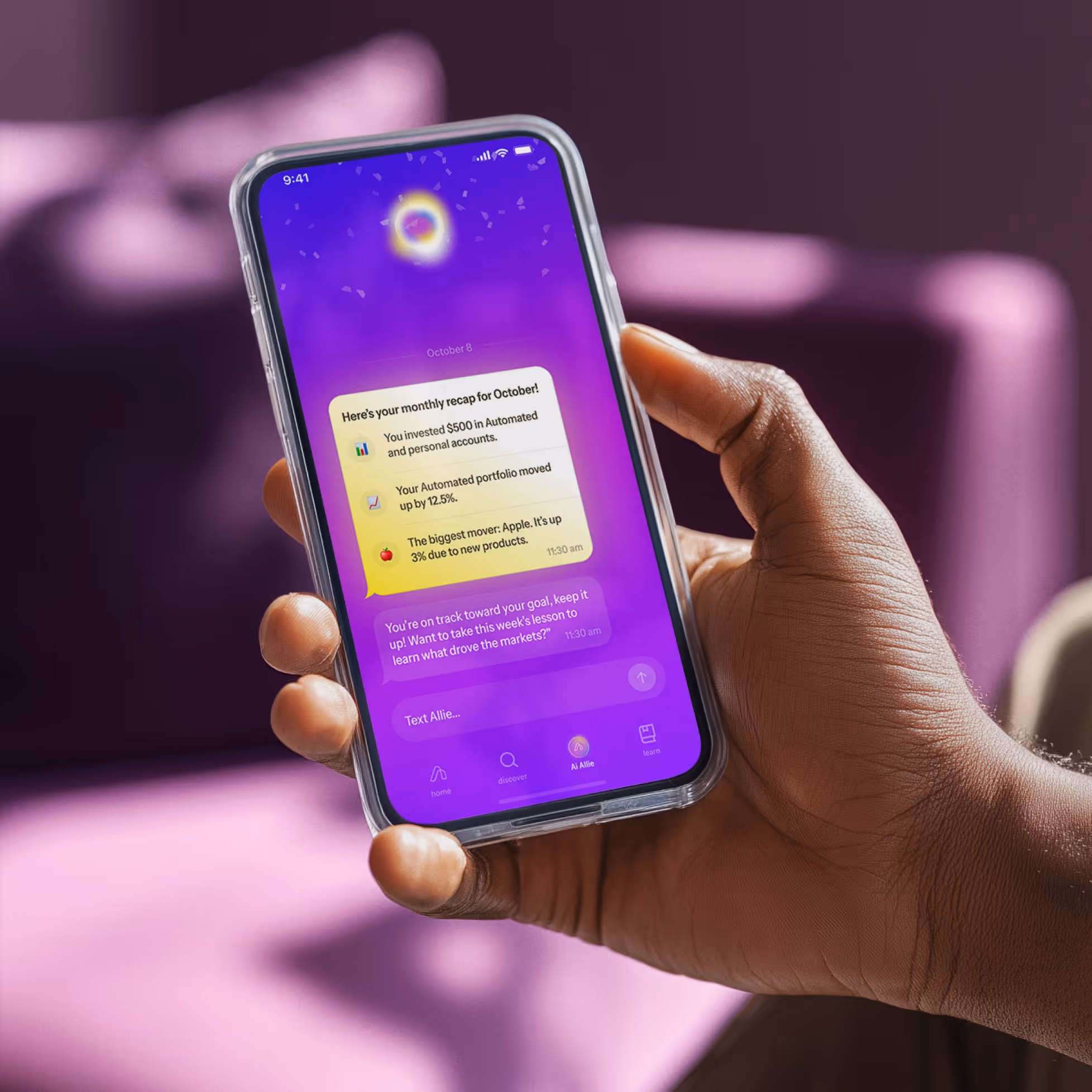 Hand holding smartphone displaying an investment app with a monthly recap and text messages on a purple background.