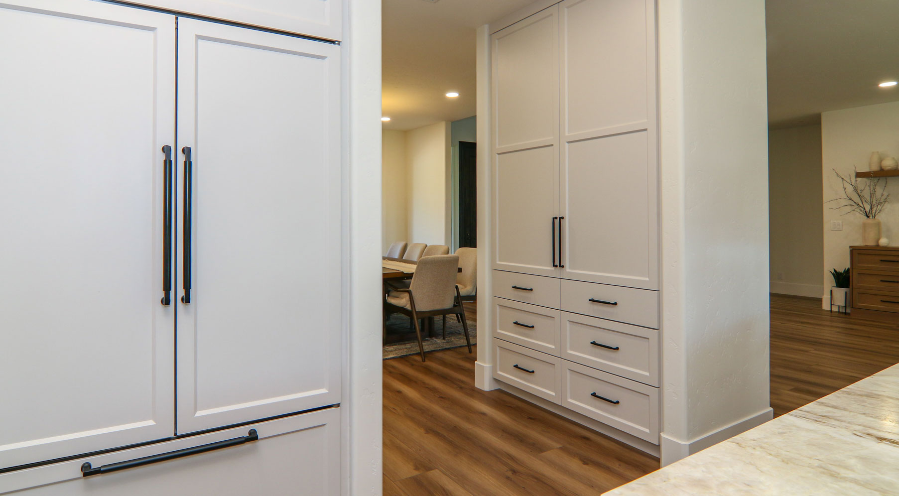 Stylish modern kitchen in Penryn, CA featuring white cabinets with black handles and warm wood flooring.
