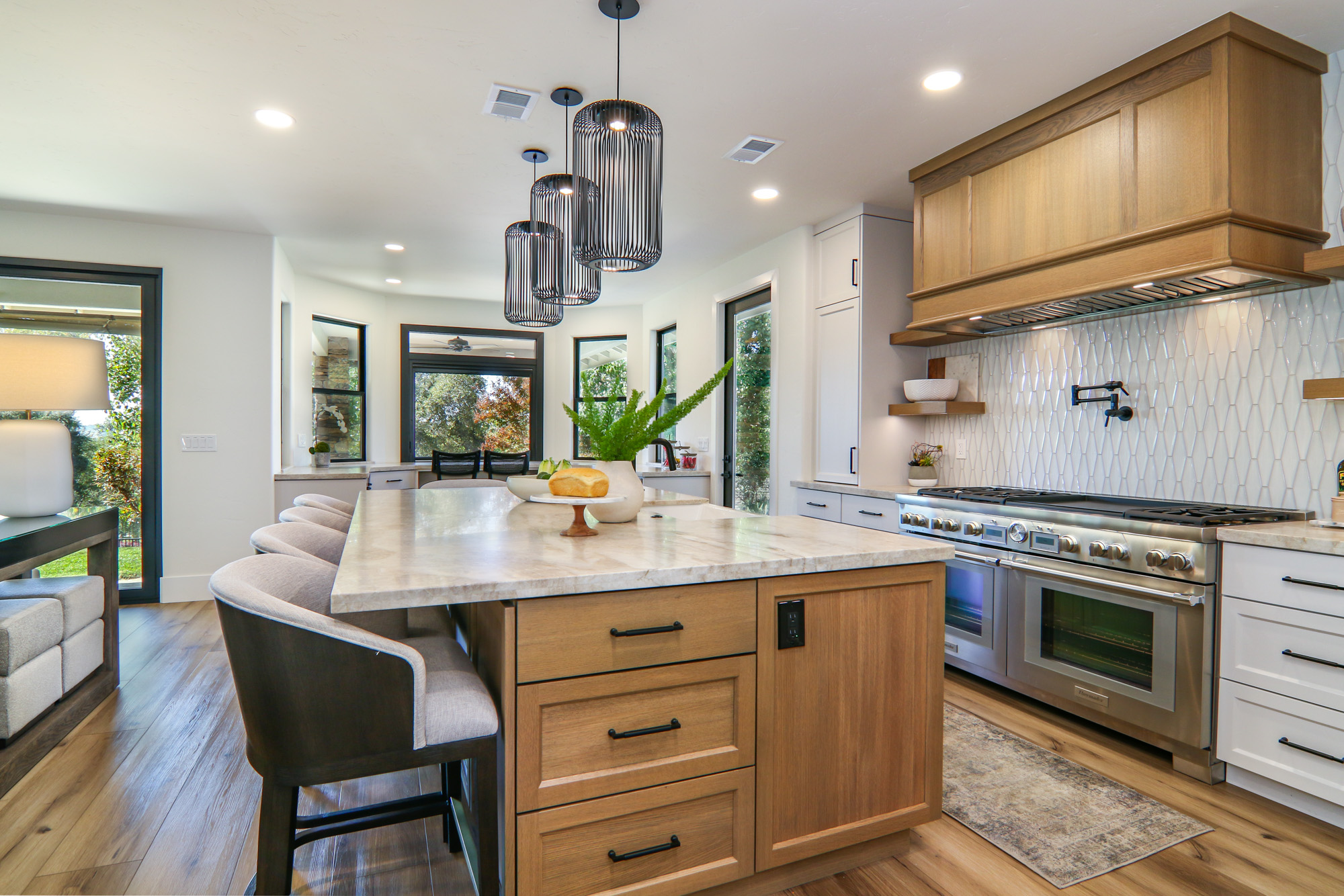 Modern kitchen remodel in Penryn, CA featuring wood cabinets, stylish pendant lights, and a spacious island with a stone countertop.