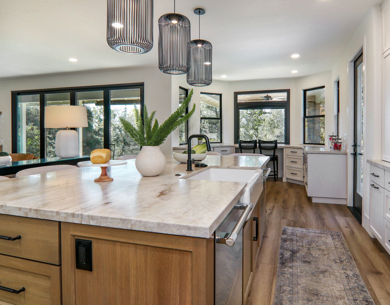 Modern kitchen with gray and wood cabinets, pendant lights, and large windows in Penryn, CA.