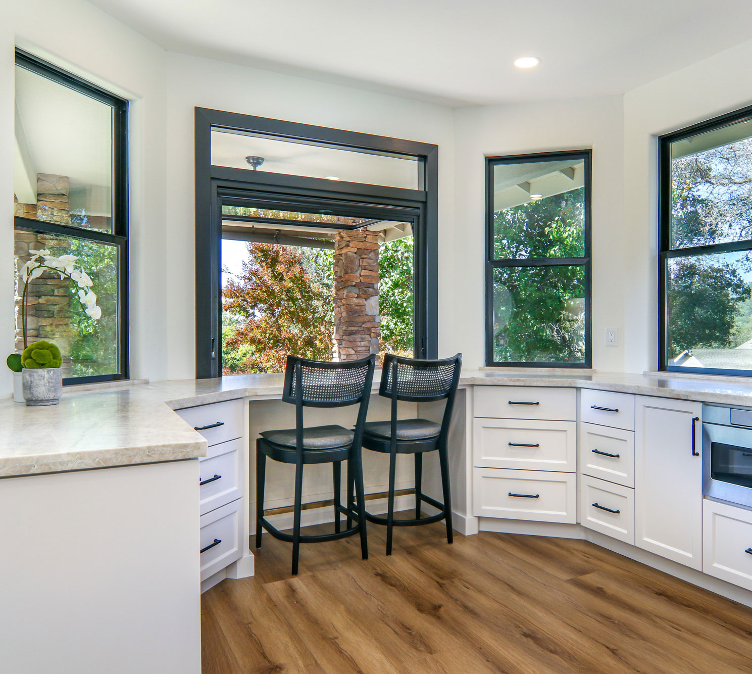 Modern kitchen nook with black bar stools, stone pillar, and large windows in Penryn, CA.