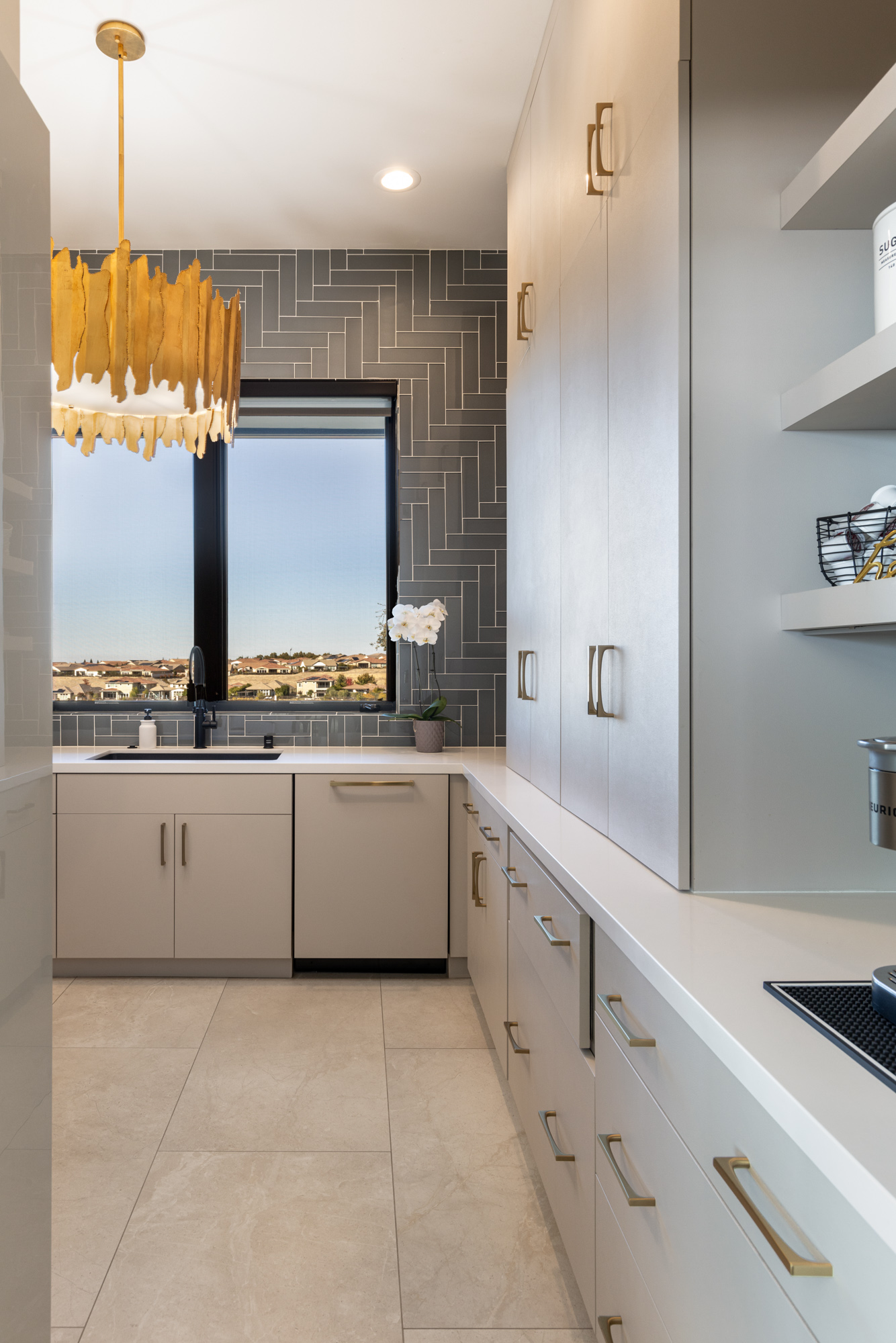 Modern kitchen remodel in Lincoln, CA featuring gold accents, sleek cabinetry, and herringbone tile backsplash.