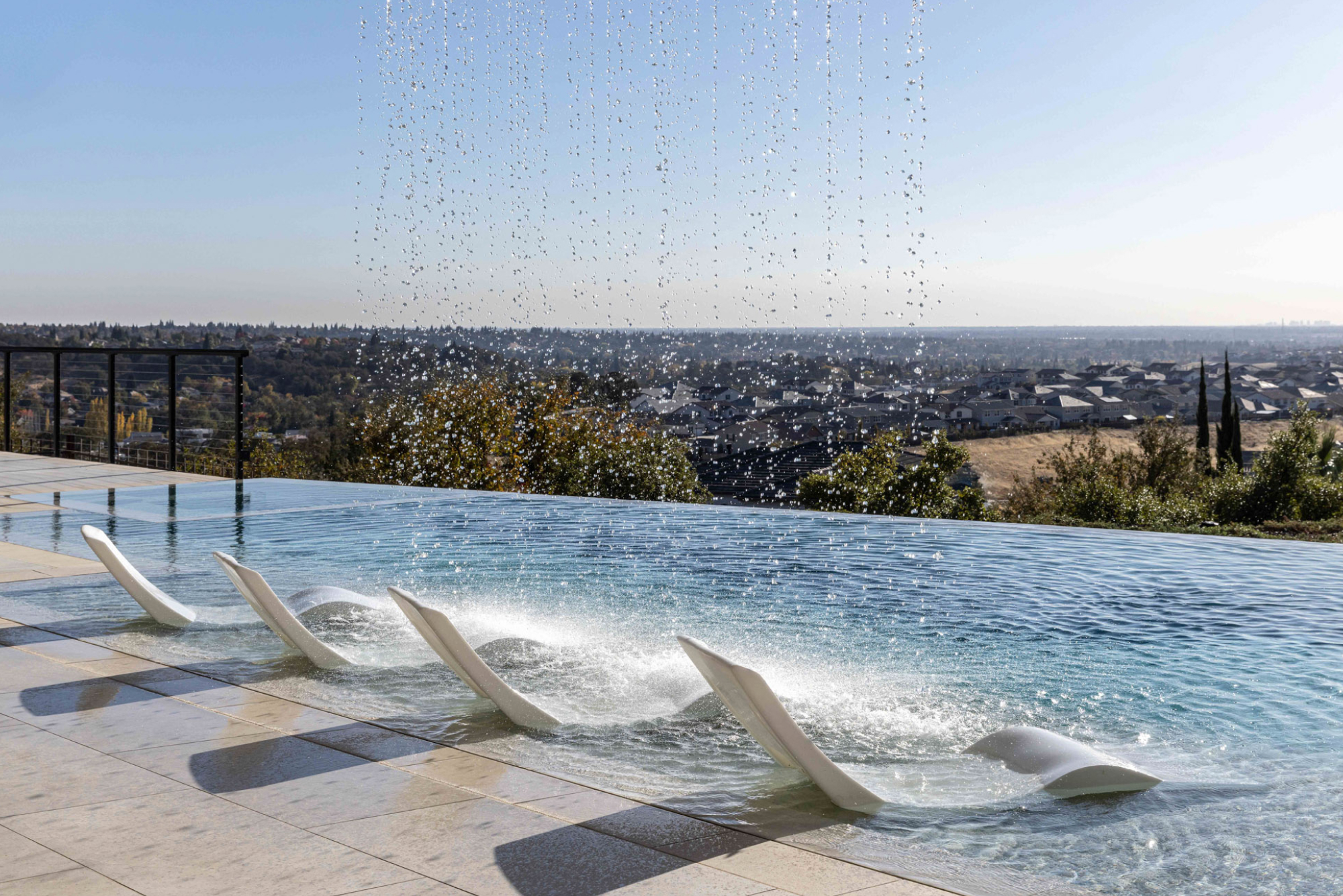 Modern infinity pool with waterfall feature in Lincoln, CA, overlooking scenic views.