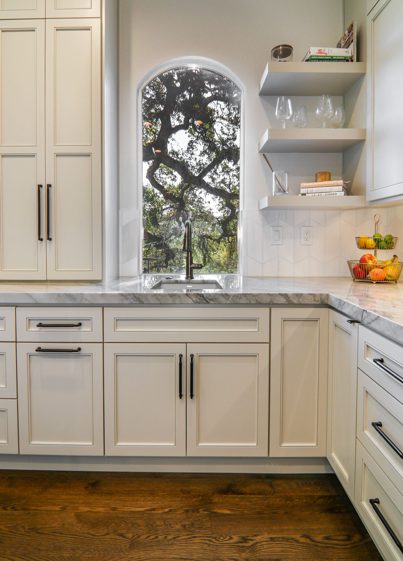 Stylish modern kitchen with white cabinetry, marble countertops, and a view of nature in Roseville, CA.