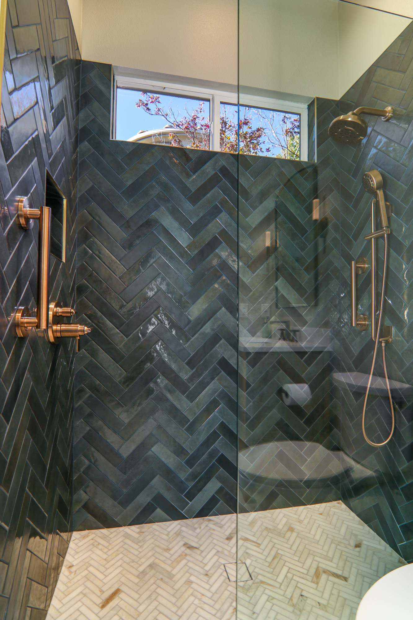 Stylish bathroom remodel in Roseville, CA featuring herringbone tile pattern, modern fixtures, and glass-enclosed shower.