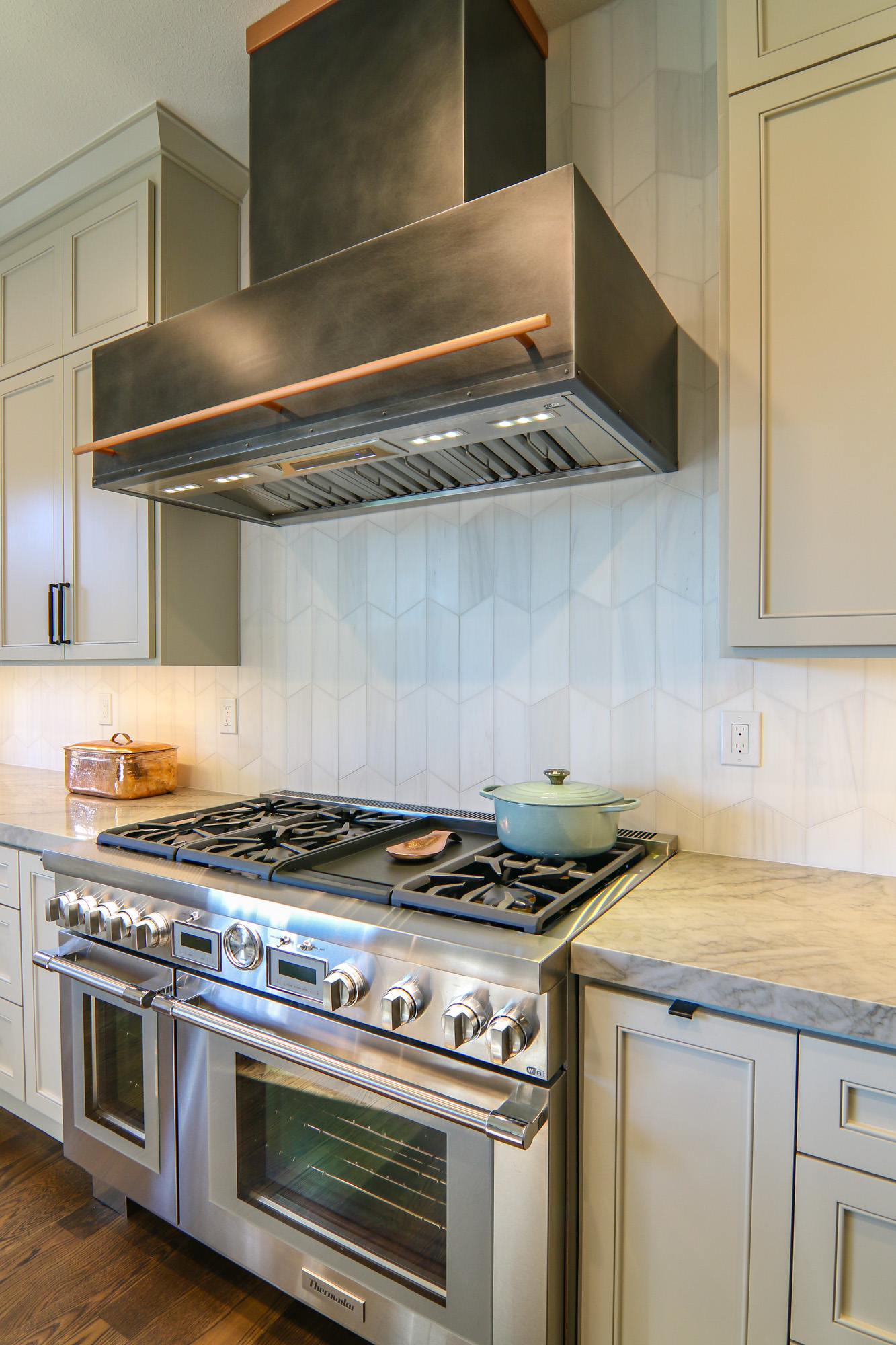 Luxury kitchen remodel in Roseville, CA featuring a stainless steel range, marble countertops, and a modern hexagonal backsplash.