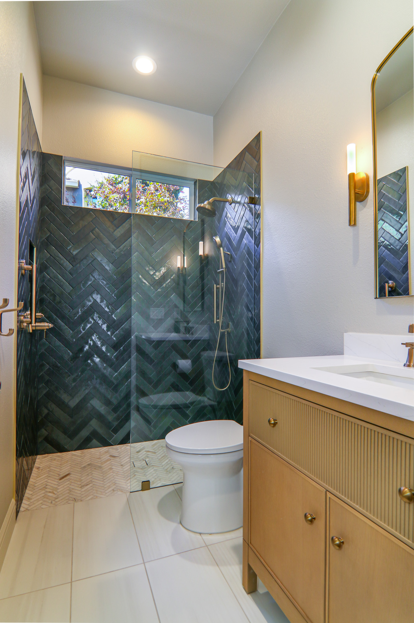 Stylish bathroom remodel in Roseville, CA featuring a herringbone tile shower, modern lighting, and a sleek vanity.