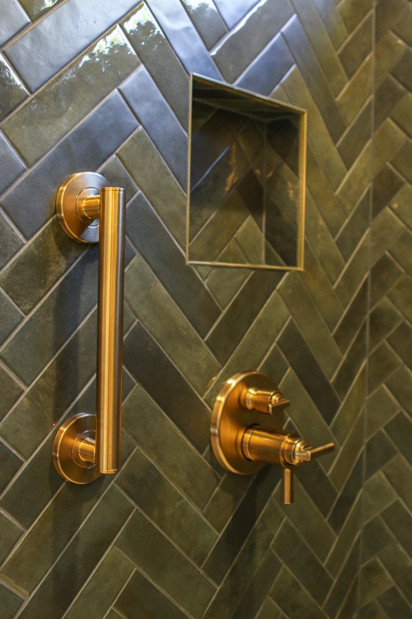 Luxurious bathroom featuring green herringbone tile and brushed gold fixtures in Roseville, CA.