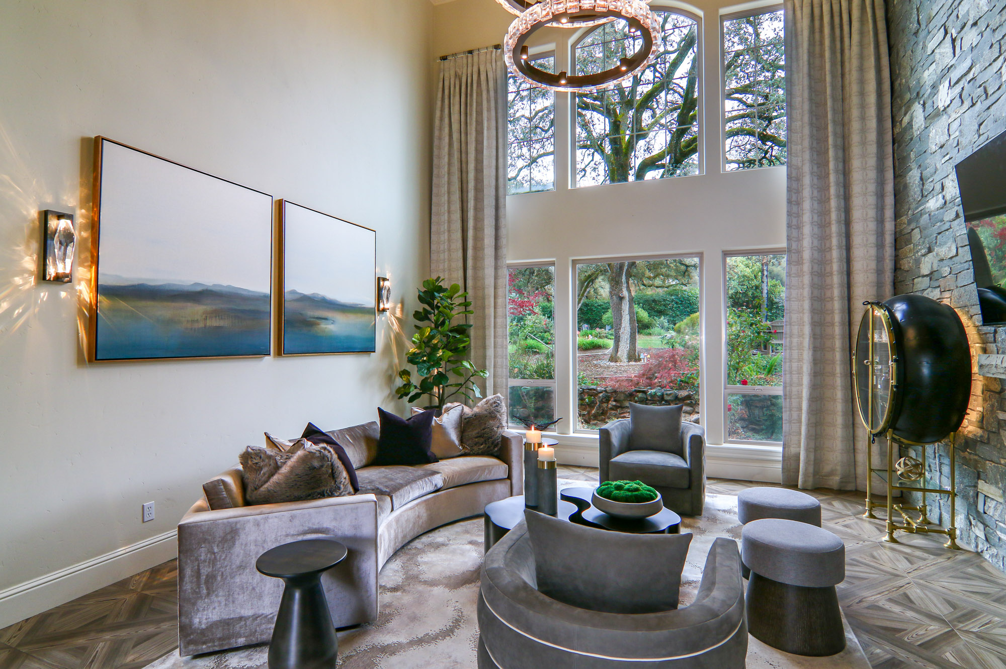 Modern living room in Lincoln, CA, featuring a curved velvet sofa, large windows with garden views, and elegant decor.