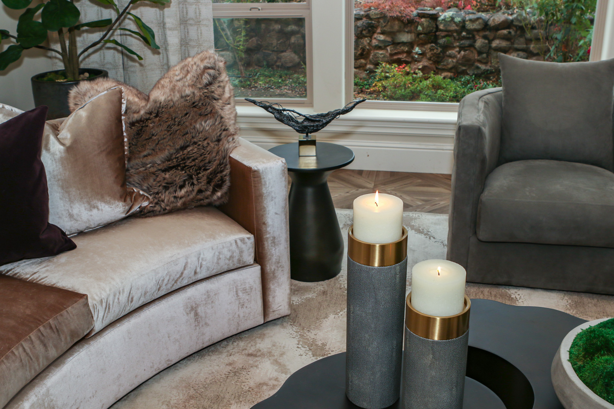 Modern living room design in Lincoln, CA featuring a curved velvet sofa, decorative candles, and contemporary accents.