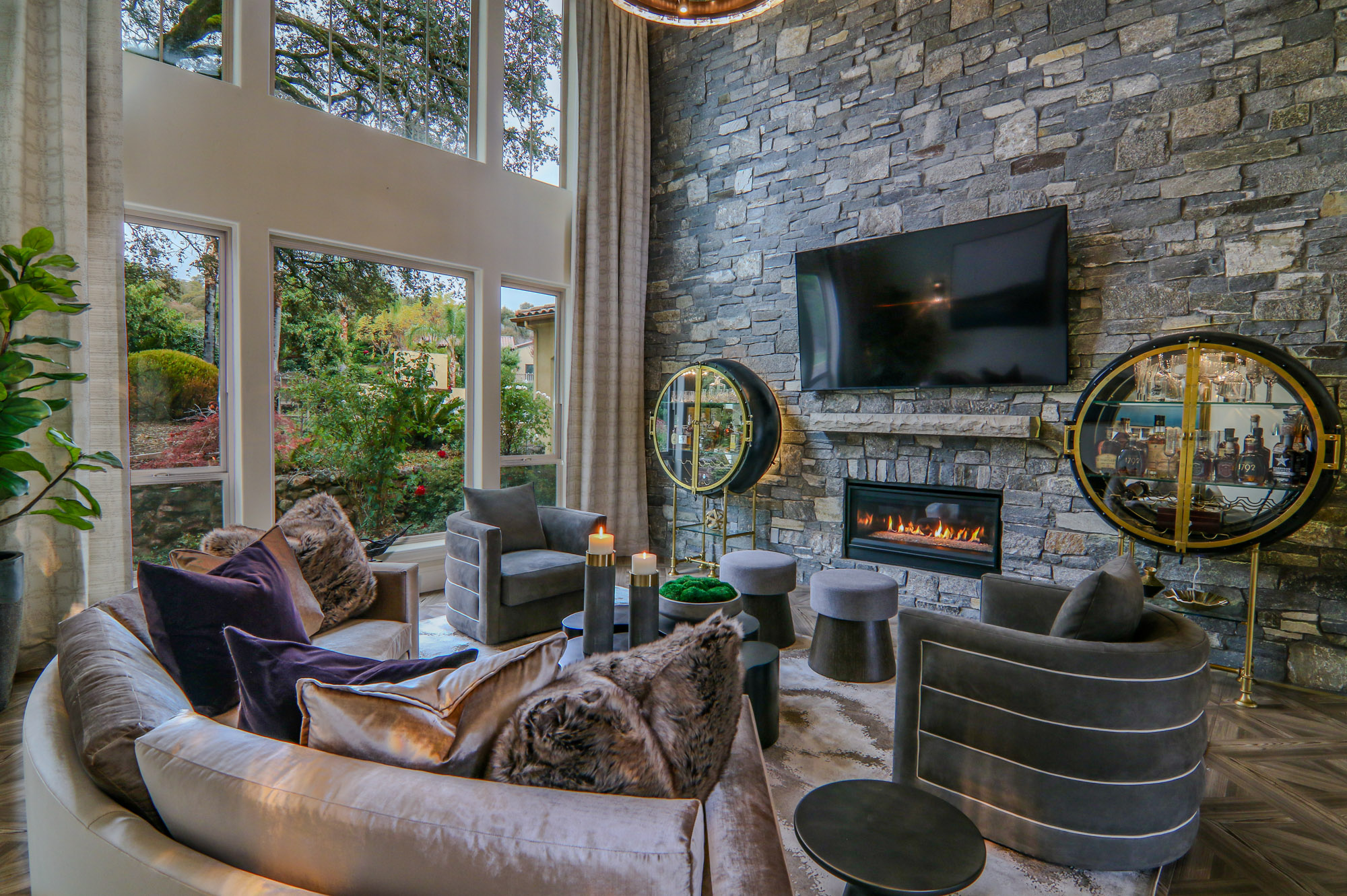 Modern living room with a stone fireplace, large windows, and chic furnishings in Lincoln, CA.