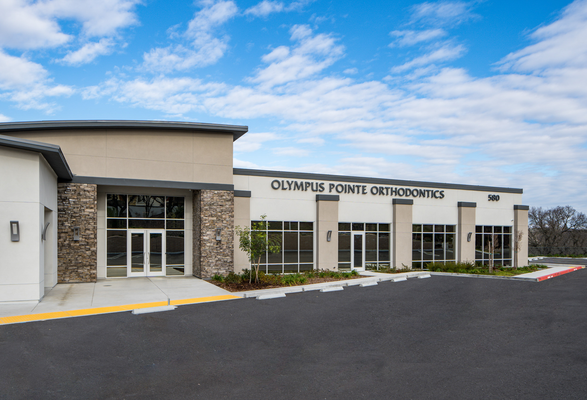 Contemporary exterior of Olympus Pointe Orthodontics in Roseville, CA with stone accents and large windows.