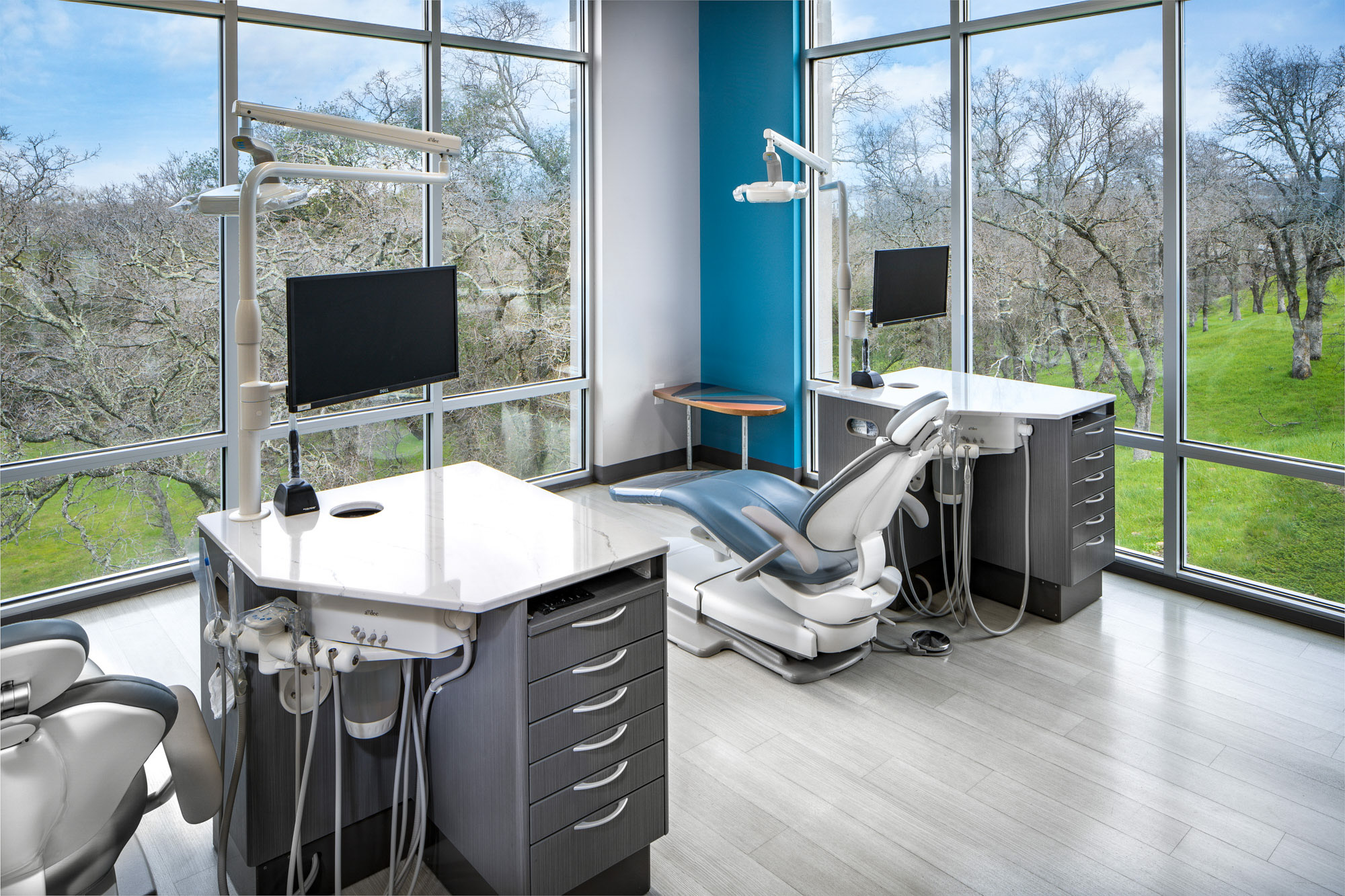 Modern dental patient care area with large windows, white dental chairs, and gray cabinetry in Roseville, CA