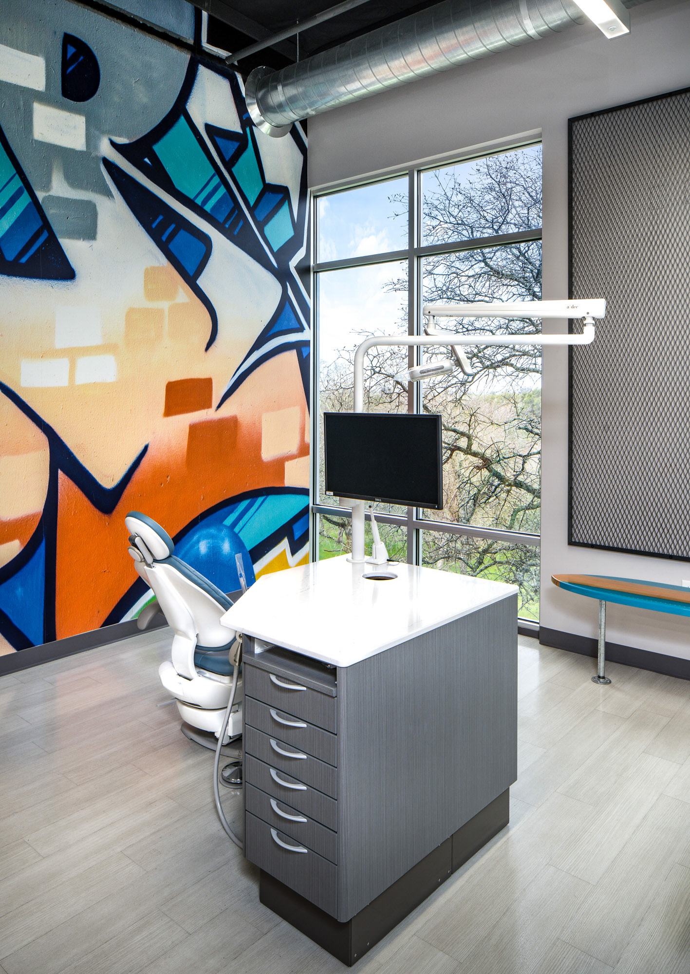 Modern dental office in Roseville, CA featuring a unique graffiti wall art, ergonomic dental chair, and large windows.