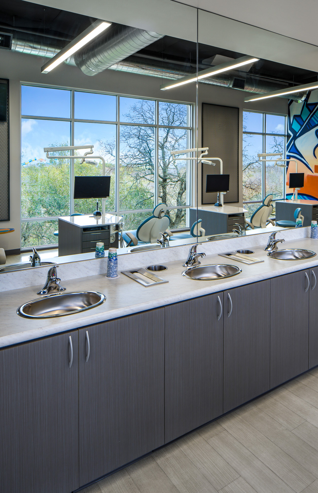 Modern dental office sink with grey cabinetry and marble countertop in Roseville, CA, featuring dual sinks and large windows.
