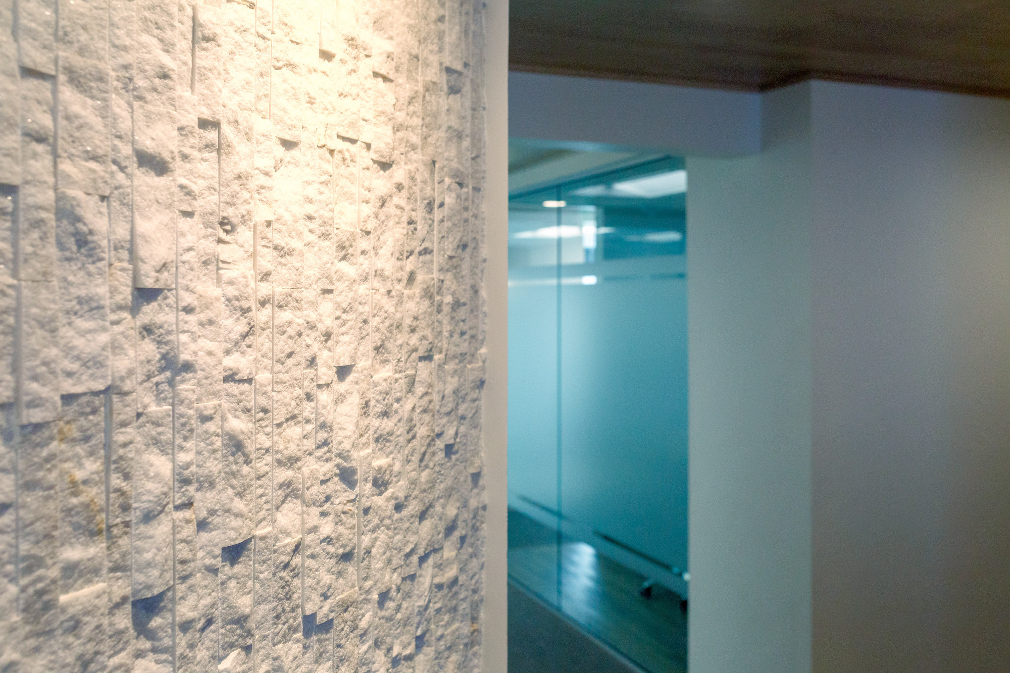 Textured stone wall detail in a modern dental office in roseville, california, with glass panels and wooden flooring.
