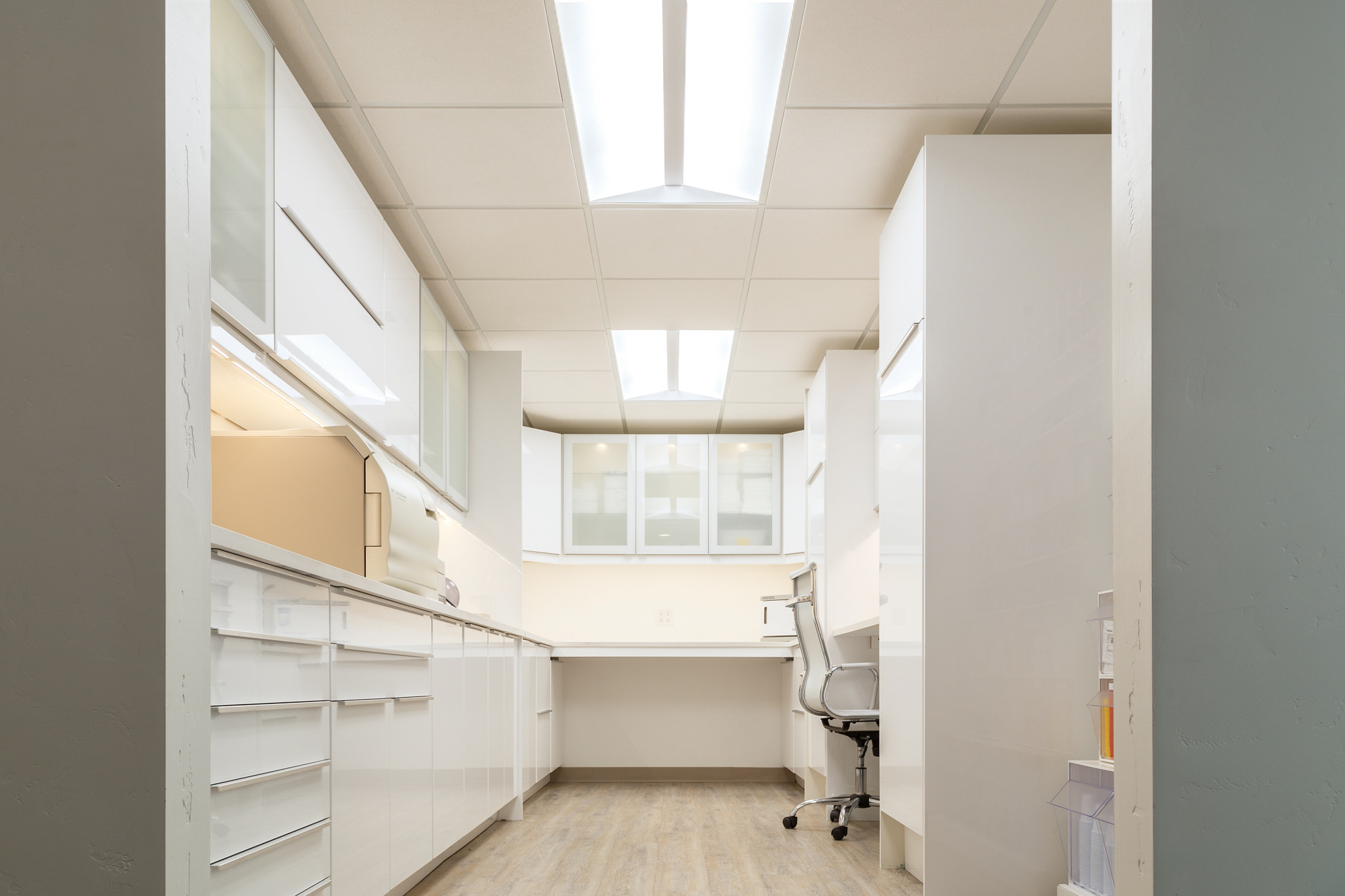 Modern dental office workspace with white cabinetry and wooden floors in a Roseville, California design.
