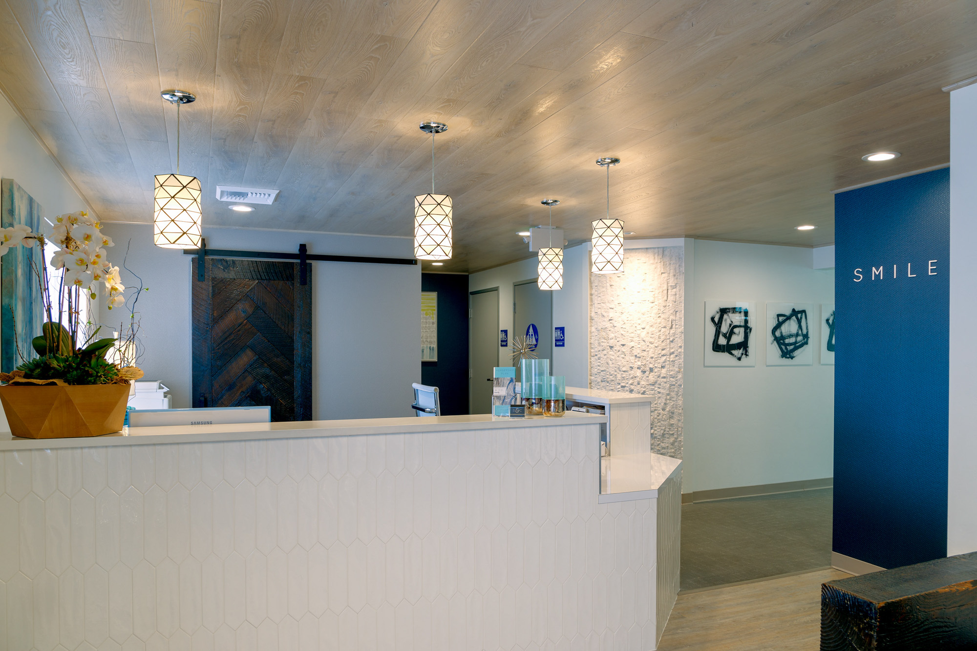 Contemporary dental office reception with geometric pendant lights and textured walls in roseville, california