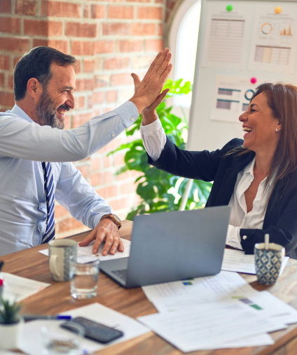 Fundraising professionals celebrating successful campaign milestone with high five in office