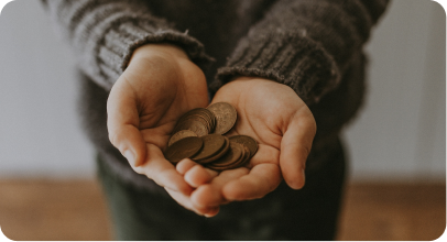 Close-up of hands cupped together holding several coins against a blurred background.