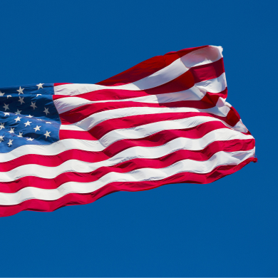 United States flag waving against a clear blue sky.