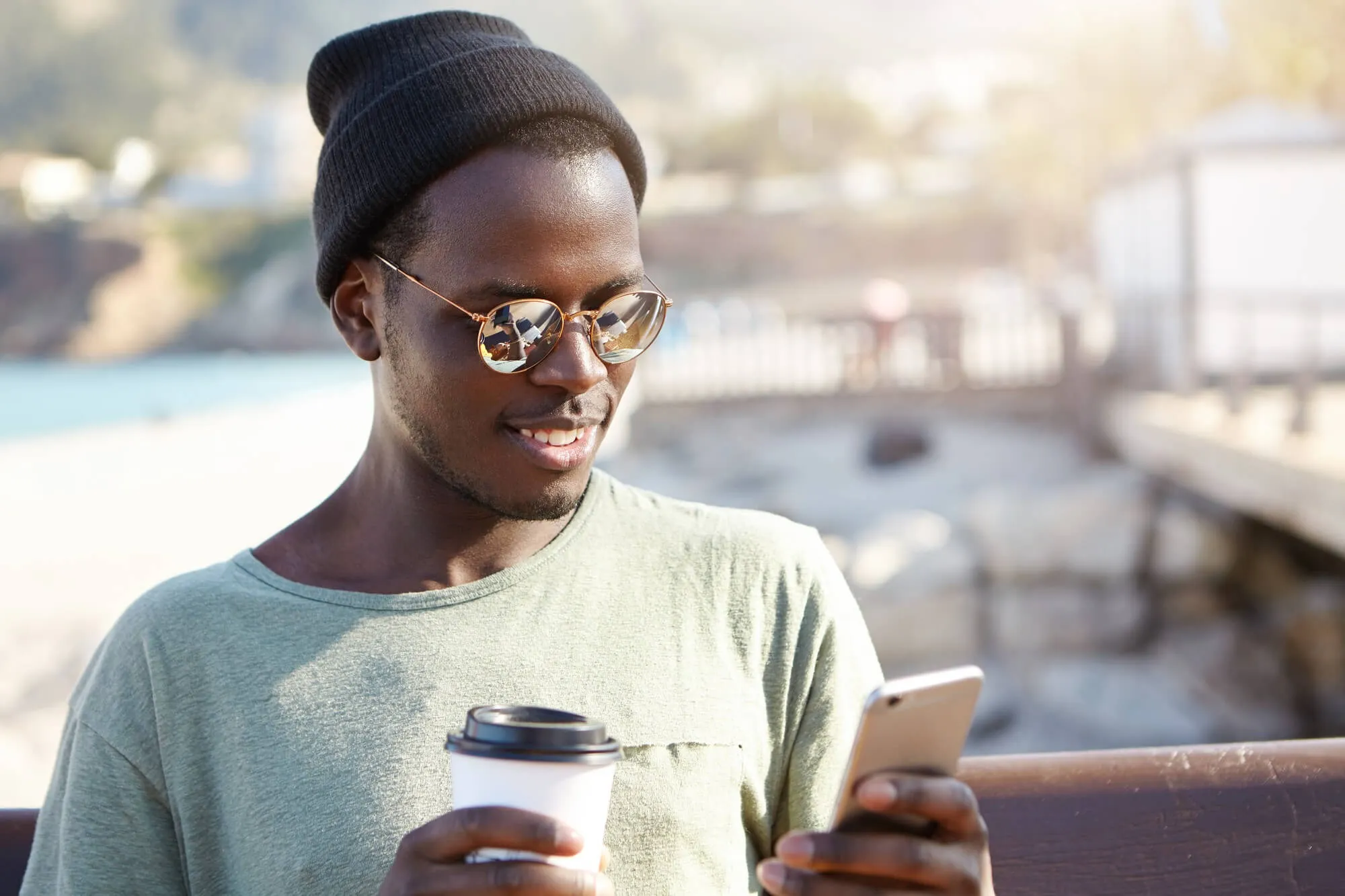 A man holding a cup of coffee and looking at a cell phone.