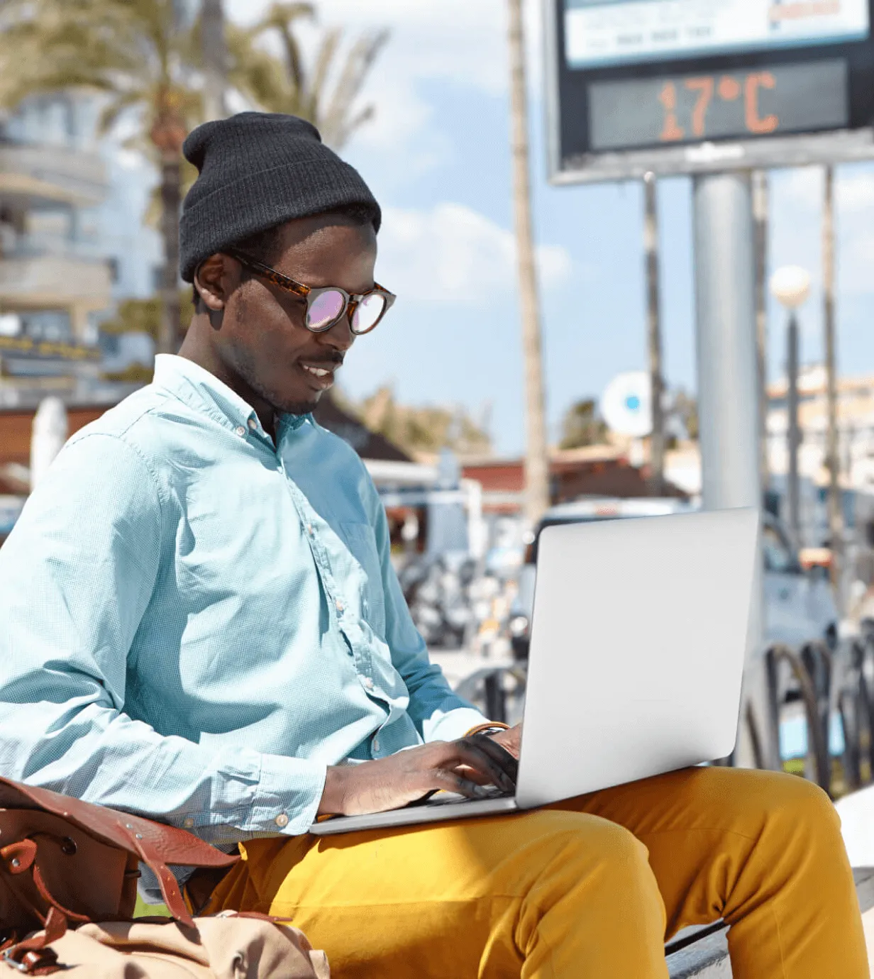A man sitting on a bench using a laptop computer.