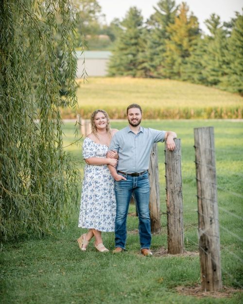 Dr. Isaac Reis and Dr. Ronni Reis engagement photo along a fence in the park in Davenport, Iowa where they first met.