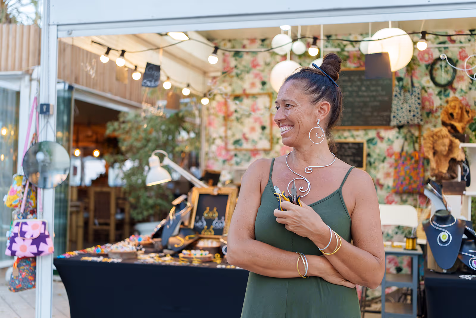 Woman in green dress standing at artisan jewelry booth at Washington County farmers market