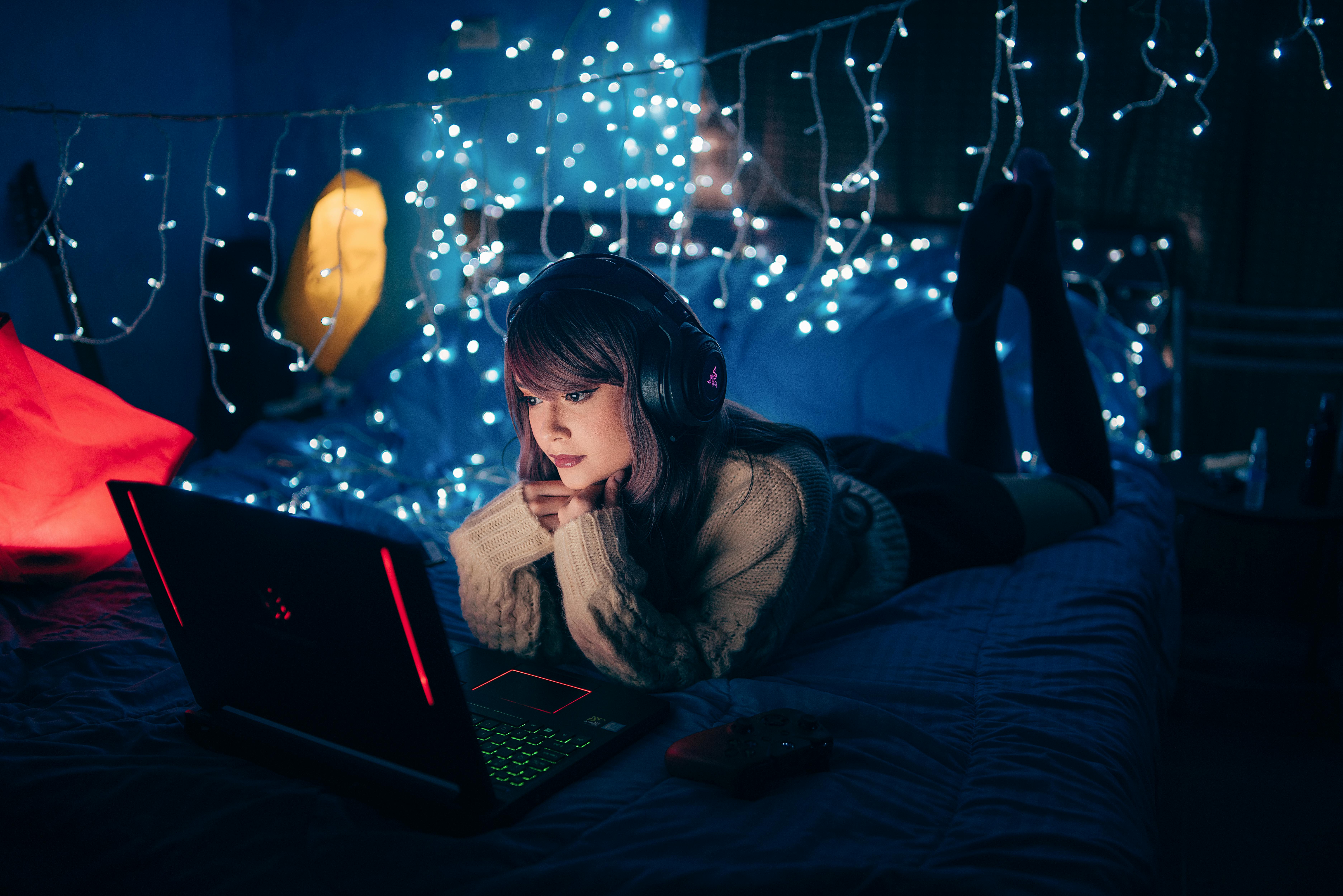 Photo of girl laying in bed with gaming laptop