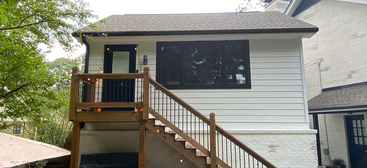 An accessory dwelling unit built above a garage with a wooden staircase and string lights