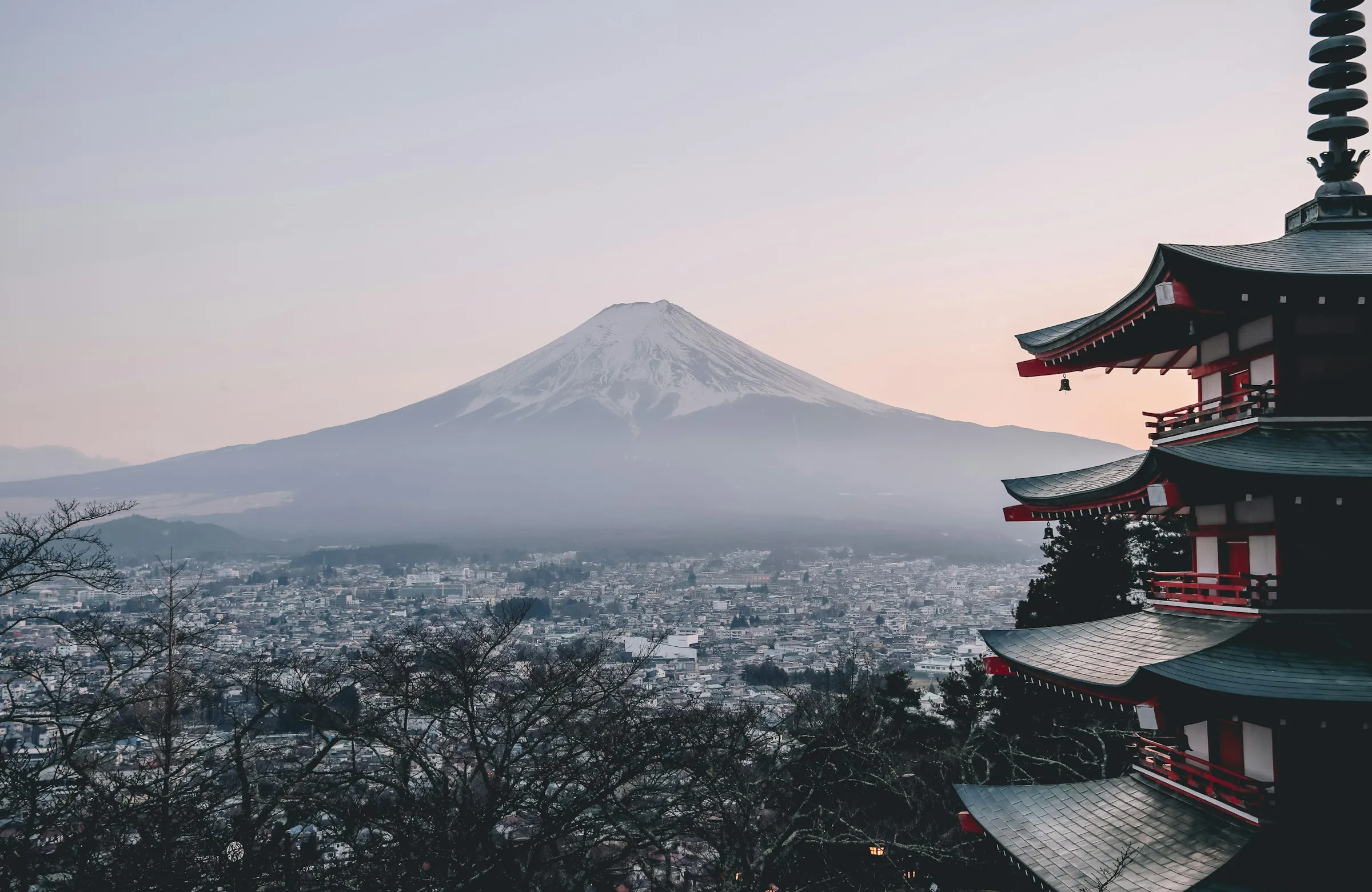 View of Mount Fuji with a traditional Japanese pagoda in the foreground during dusk.